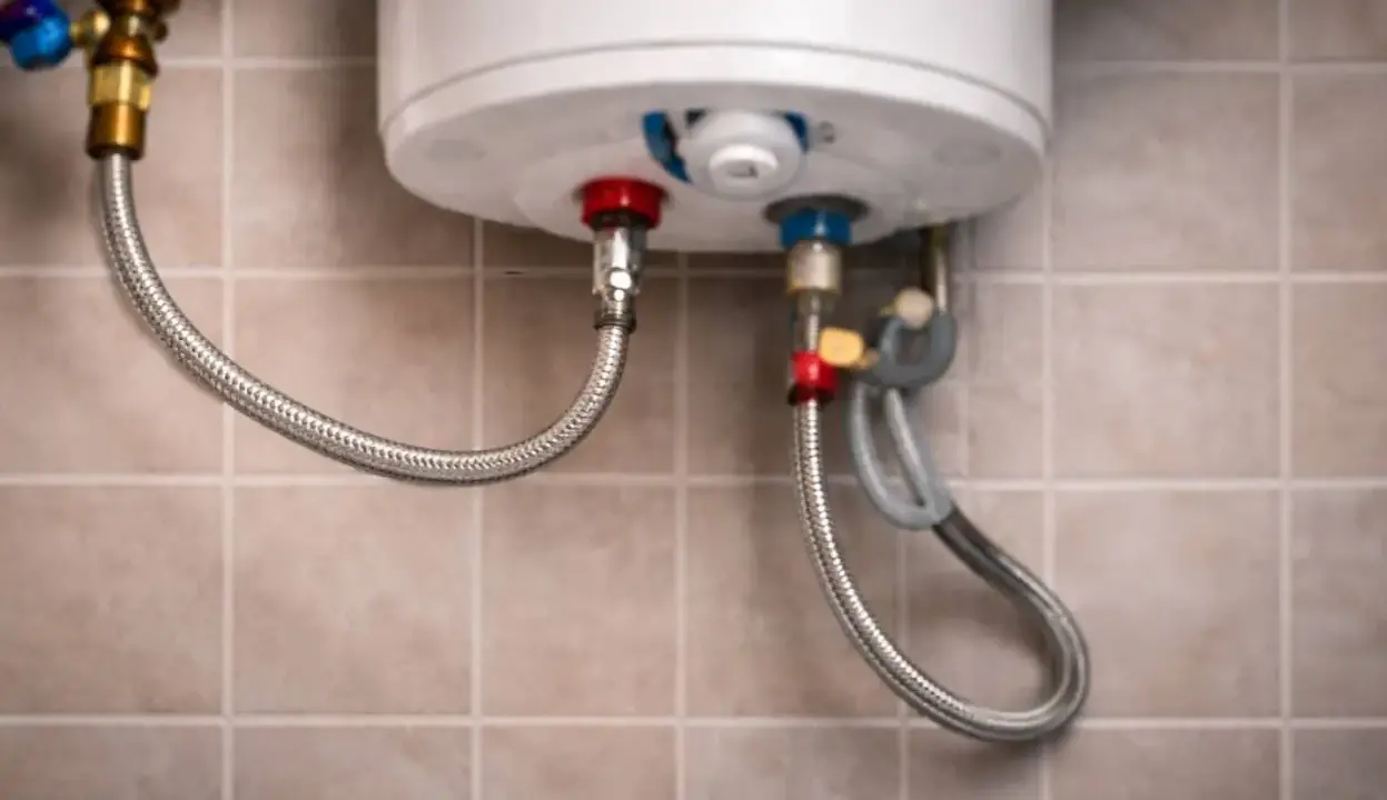 Detalle de conexiones de un termo eléctrico. Se observa una manguera flexible conectada a la válvula de seguridad, indicando que el termo eléctrico gotea por ahí.