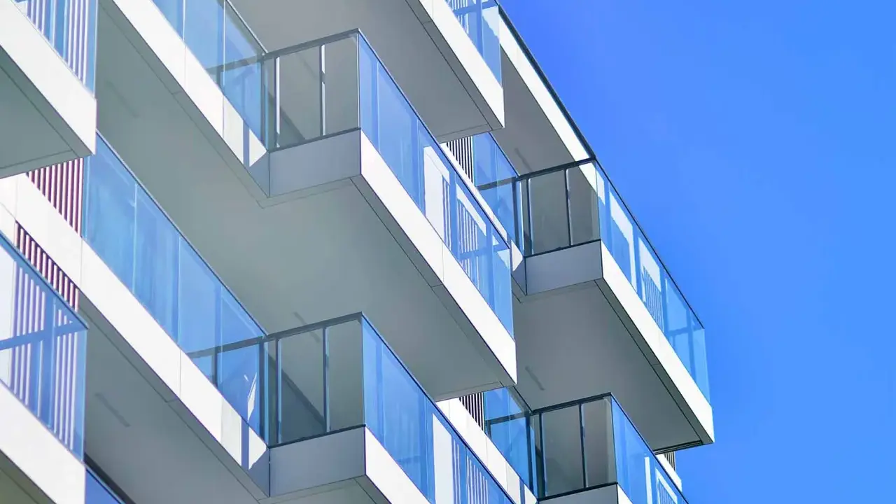 Balcones modernos de un edificio blanco con barandillas de cristal azul contra un cielo despejado. ¿Qué es el ITE?