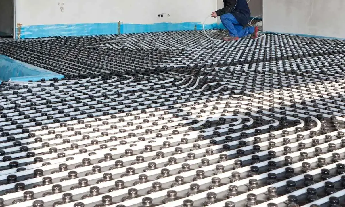 Instalación de tuberías para que se pueda poner suelo radiante en un piso. Un trabajador supervisa el trabajo.