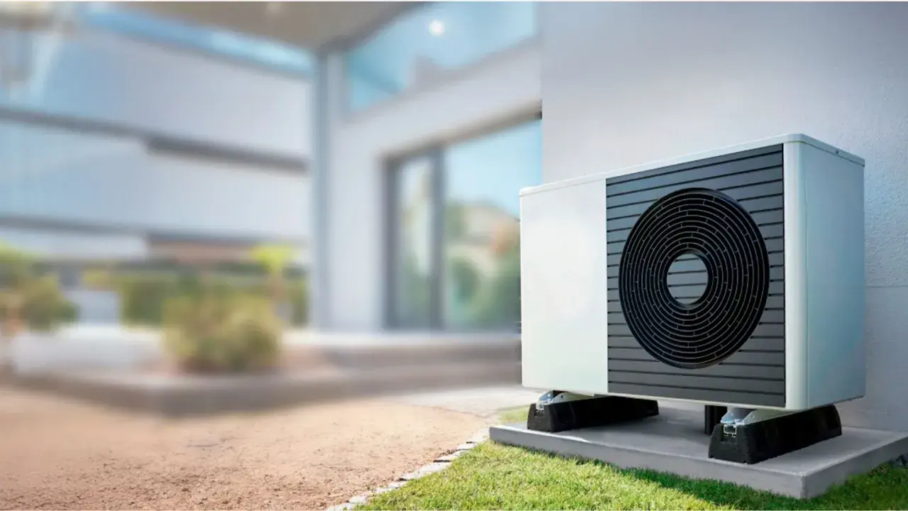 Unidad exterior de bomba de calor instalada junto a una casa moderna, lista para climatizar el piso.