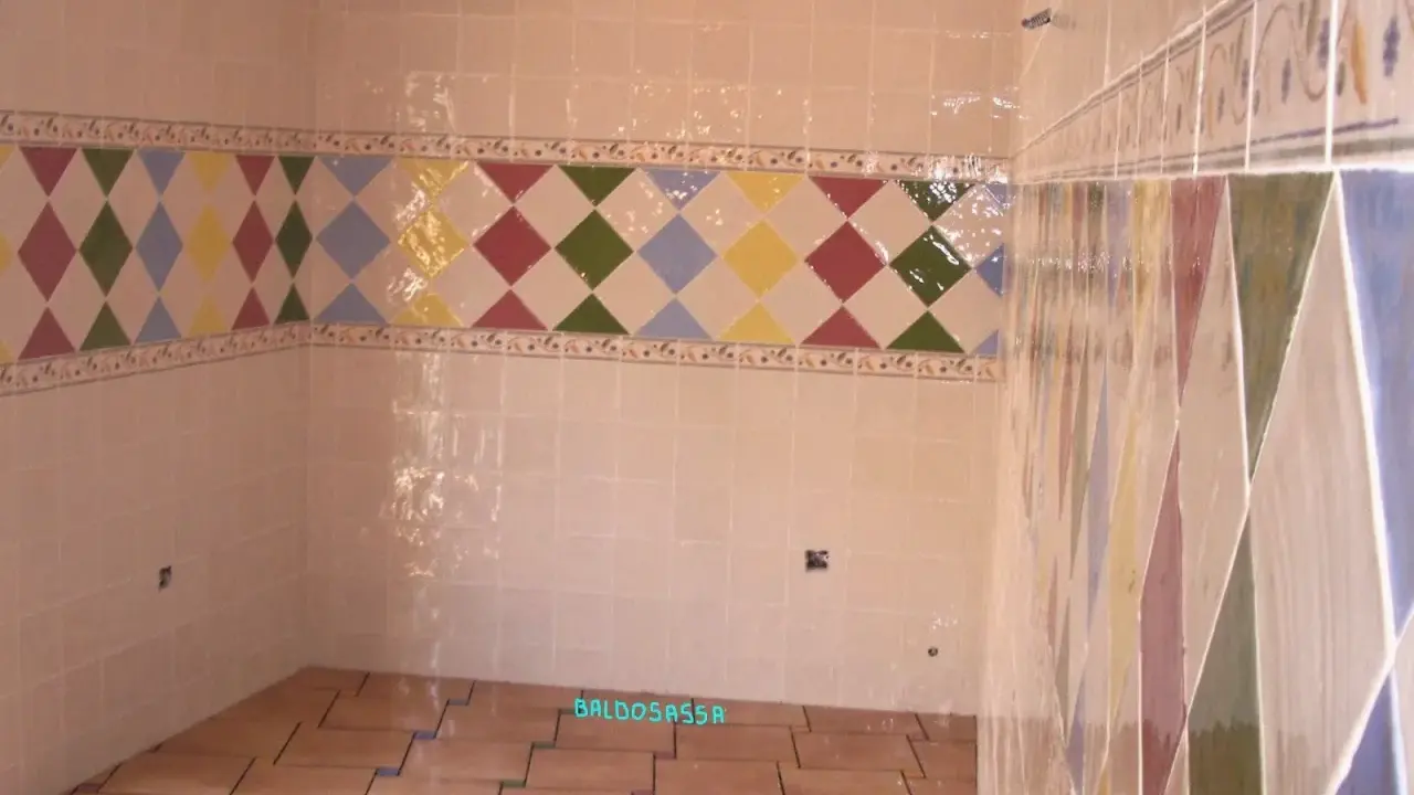 Detalle de azulejos en una pared, mostrando la diferencia entre mortero capa fina y capa gruesa en un diseño de rombos.