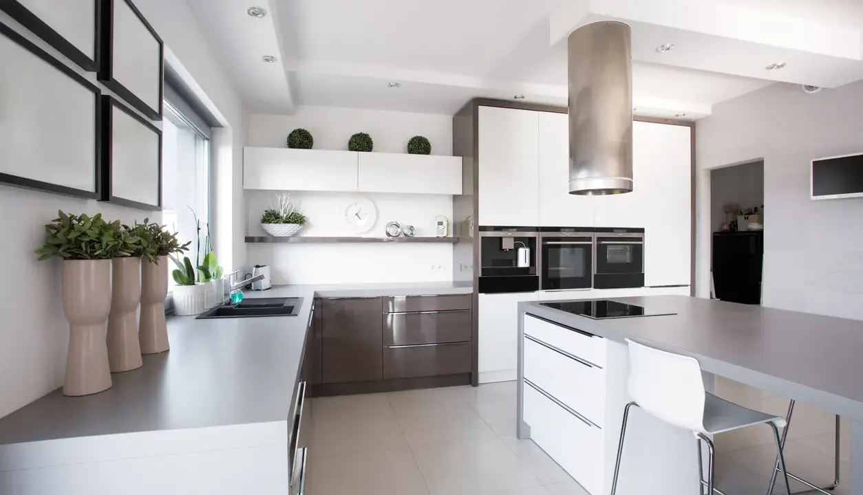 Cocina moderna con isla central y campana extractora cilíndrica. Es obligatorio tener campana extractora en la cocina para mantener el aire limpio.