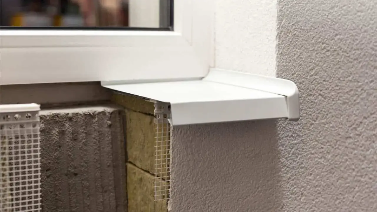 Detalle constructivo de un alféizar blanco sobre aislamiento y mampostería, con malla de refuerzo visible.