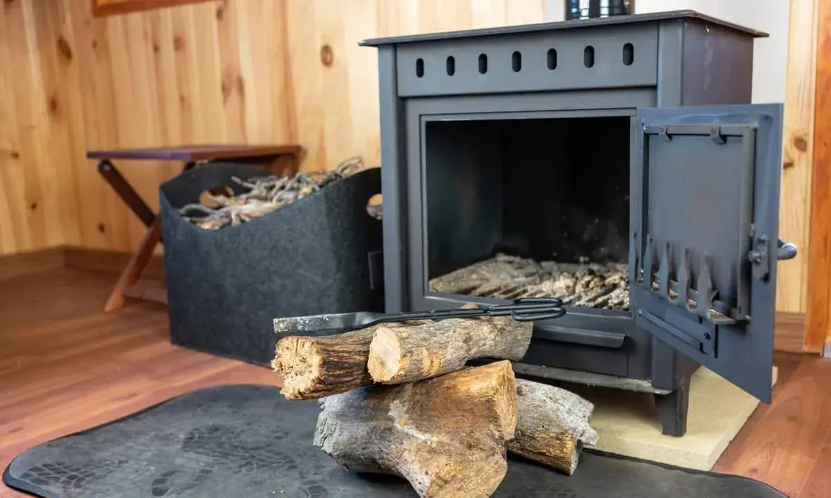 Estufa de hierro con leña y herramientas. Aprende como limpiar chimenea de hierro por fuera para mantenerla impecable.