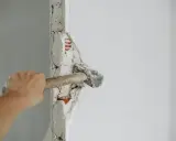 Mano golpeando un tabique con un martillo. La pregunta de cuanto se tarda en tirar un tabique depende de la habilidad y el material.