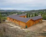 Edificio de madera en forma de L, con tejado oscuro, en un paisaje rural. Ideal para saber cuántos metros cuadrados se pueden construir sin proyecto.