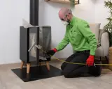 Hombre con equipo de protección, usando una herramienta para limpiar el tubo de una chimenea de leña.