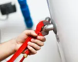 Mano con llave roja ajustando tubería. Es parte de la revisión caldera gas obligatoria para garantizar seguridad y eficiencia.