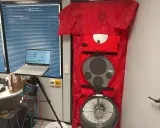 Equipo para blower door test en puerta, con laptop mostrando datos y medidor de presión.