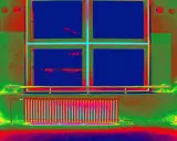 Radiador y ventana con colores falsos que resaltan el **puente térmico** en la pared.