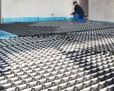 Instalación de tuberías para que se pueda poner suelo radiante en un piso. Un trabajador supervisa el trabajo.