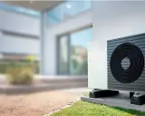 Unidad exterior de bomba de calor instalada junto a una casa moderna, lista para climatizar el piso.