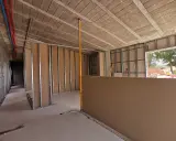 Construcción interior con estructura metálica y paneles de **ladrillo o pladur**. Se ven tuberías de agua y un nivelador.