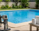 Sistema de filtración y depósitos blancos junto a una piscina azul, ilustrando como funciona una piscina de sal.