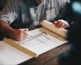 Arquitecto dibuja planos detallados, calculando la superficie edificable para un nuevo proyecto.