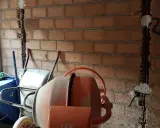 Preparativos para como tirar tabiques de ladrillo: carretilla, hormigonera y pared con ranuras para cables.