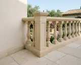 Una elegante balaustrada de piedra con balaustres torneados, que delimita un patio con baldosas y un jardín con flores púrpuras.