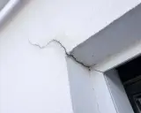 Grietas en pared blanca, indicando necesidad de mantenimiento sate.