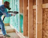 Un trabajador con equipo de protección rocía espuma aislante, mostrando la diferencia entre poliuretano y poliestireno en la construcción.