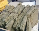 Fardos de lana de roca, material aislante que puede ser tóxico si no se maneja con cuidado, apilados junto a paneles de techo.