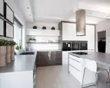 Cocina moderna con isla central y campana extractora cilíndrica. Es obligatorio tener campana extractora en la cocina para mantener el aire limpio.