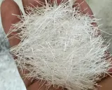 Mano sosteniendo un puñado de fibra de vidrio aislante, que puede ser tóxico.