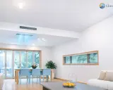 Instalación de aire acondicionado por conductos en un salón moderno. El sistema distribuye aire fresco de forma discreta.