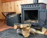 Estufa de hierro con leña y herramientas. Aprende como limpiar chimenea de hierro por fuera para mantenerla impecable.