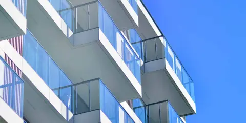 Balcones modernos de un edificio blanco con barandillas de cristal azul contra un cielo despejado. ¿Qué es el ITE?
