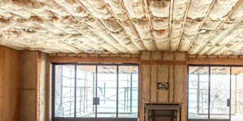 Techo con aislamiento de lana de vidrio, material que es inflamable. Ventanales y chimenea en construcción.