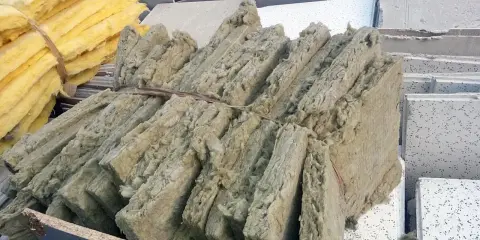 Fardos de lana de roca, material aislante que puede ser tóxico si no se maneja con cuidado, apilados junto a paneles de techo.