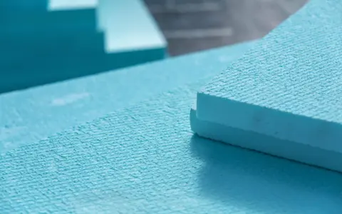 Planchas de poliestireno extruido (XPS) de color azul, apiladas y listas para aislamiento. El XPS es un material ligero y resistente.