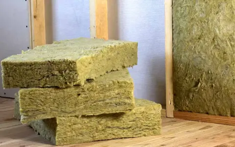 Bloques de lana mineral, un material aislante, apilados sobre madera. Así es que es la lana mineral.