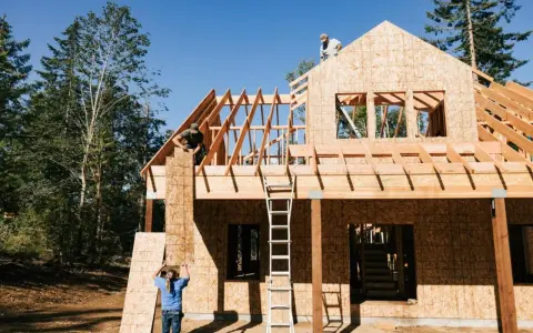 Obreros trabajan en la estructura de madera de una casa, mostrando los pasos a seguir para construir una casa.
