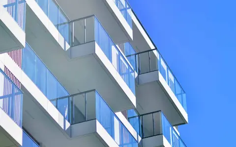 Balcones modernos de un edificio blanco con barandillas de cristal azul contra un cielo despejado. ¿Qué es el ITE?