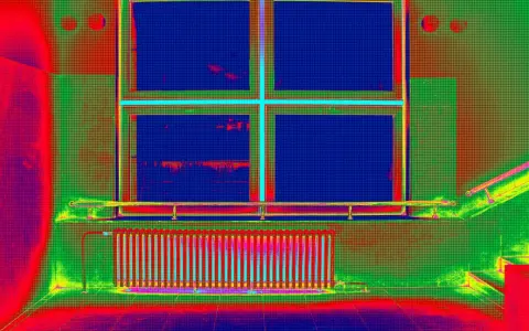 Radiador y ventana con colores falsos que resaltan el **puente térmico** en la pared.