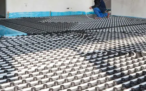 Instalación de tuberías para que se pueda poner suelo radiante en un piso. Un trabajador supervisa el trabajo.