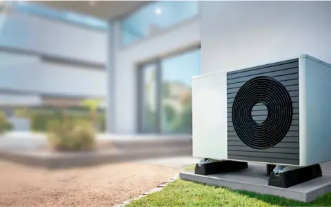 Unidad exterior de bomba de calor instalada junto a una casa moderna, lista para climatizar el piso.