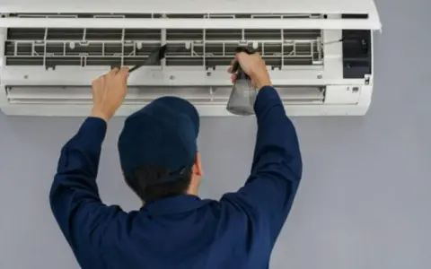 Técnico limpiando un aire acondicionado, paso clave para saber como montar aire acondicionado y mantenerlo.