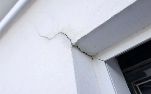 Grietas en pared blanca, indicando necesidad de mantenimiento sate.