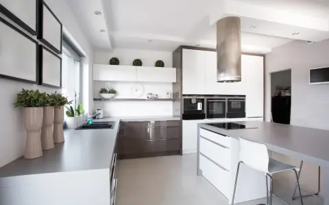 Cocina moderna con isla central y campana extractora cilíndrica. Es obligatorio tener campana extractora en la cocina para mantener el aire limpio.