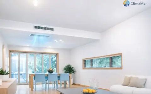 Instalación de aire acondicionado por conductos en un salón moderno. El sistema distribuye aire fresco de forma discreta.