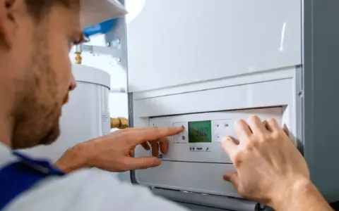 Técnico ajustando un calentador de gas butano. El esquema de instalación es complejo, pero él lo domina.