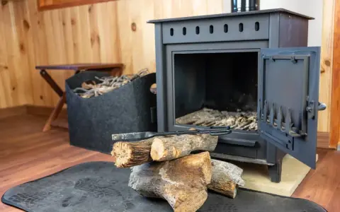 Estufa de hierro con leña y herramientas. Aprende como limpiar chimenea de hierro por fuera para mantenerla impecable.