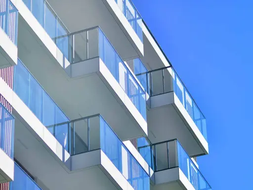 Balcones modernos de un edificio blanco con barandillas de cristal azul contra un cielo despejado. ¿Qué es el ITE?