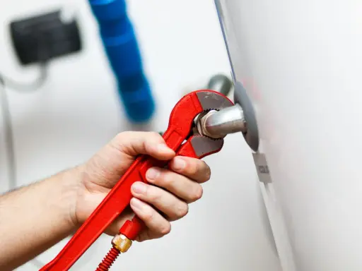Mano con llave roja ajustando tubería. Es parte de la revisión caldera gas obligatoria para garantizar seguridad y eficiencia.