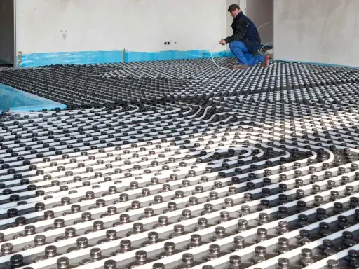 Instalación de tuberías para que se pueda poner suelo radiante en un piso. Un trabajador supervisa el trabajo.