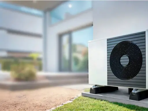 Unidad exterior de bomba de calor instalada junto a una casa moderna, lista para climatizar el piso.