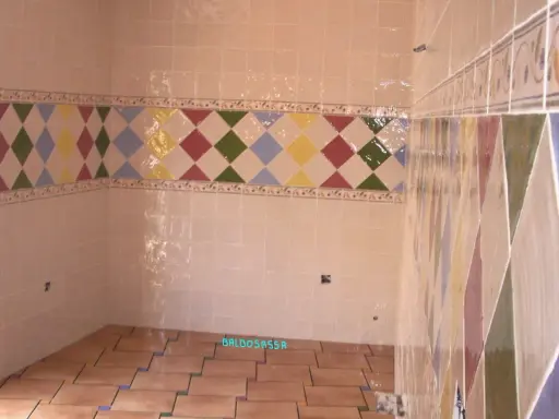 Detalle de azulejos en una pared, mostrando la diferencia entre mortero capa fina y capa gruesa en un diseño de rombos.