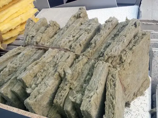 Fardos de lana de roca, material aislante que puede ser tóxico si no se maneja con cuidado, apilados junto a paneles de techo.